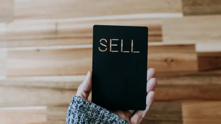 Hand holding black card with ‘SELL’ text