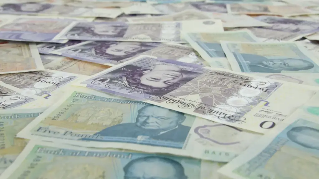 Scattered British pound banknotes on table